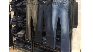 three pairs of riding jeans hanging on a rack in front of other jeans