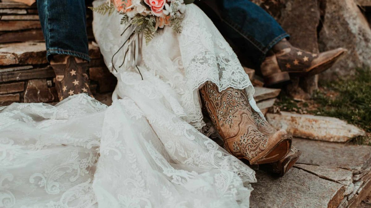 Corral wedding boots on a bride in a wedding dress holding flowers